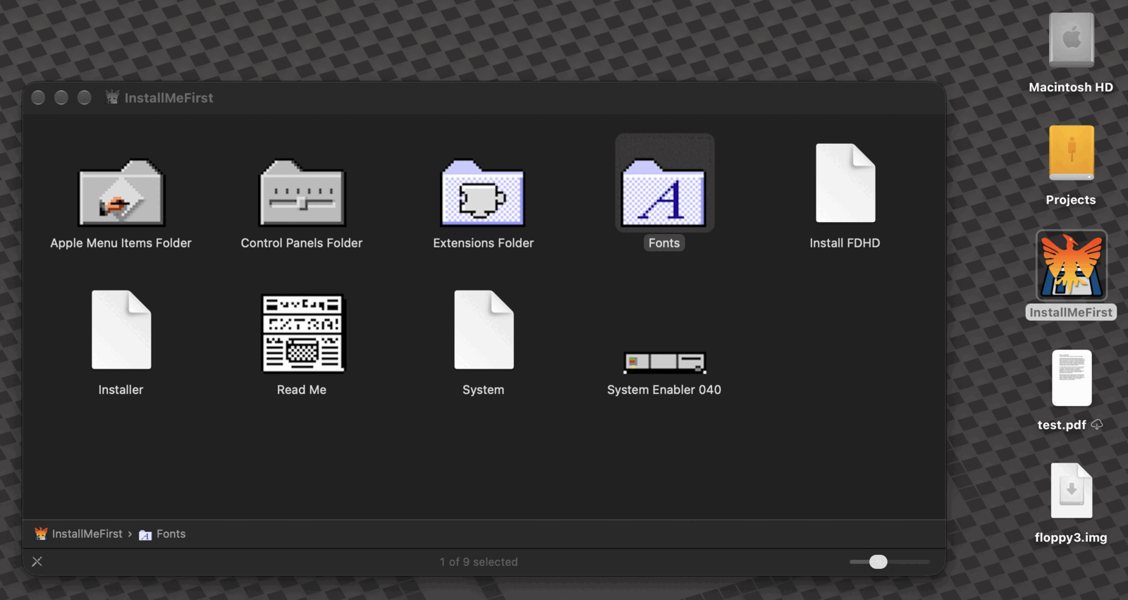 A Finder window on macOS 27 titled InstallMeFirst, showing nine items: the Apple Menu Items, Control Panels and Extensions folders and the Fonts folder with its big A, all in their classic System 7 icons, a Read Me with its classic document icon and System Enabler 040, and plain page icons for Install FDHD, Installer and System. The InstallMeFirst disk also sits on the desktop below Macintosh HD.